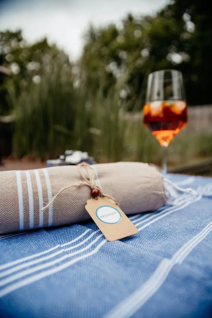 Zusammengerolltes Strandtuch liegend auf einem Tisch im Garten Marke Ecobain