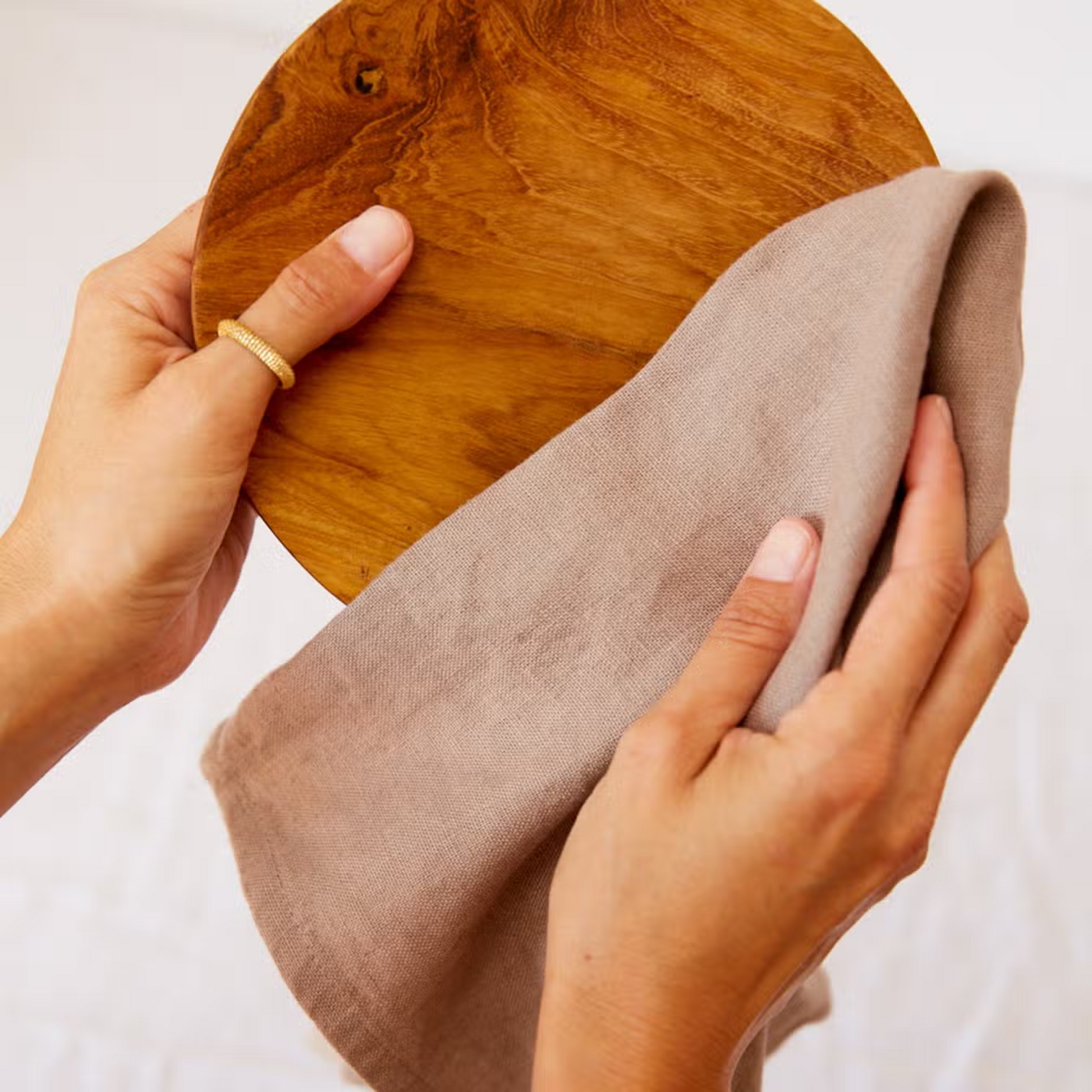 Zwei Hände reinigen eine Holzplatte mit einem grauen Geschirrtuch der Marke Greentastic